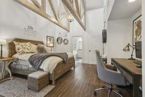 Bedroom with dark wood-style flooring, a desk, a towering ceiling, and ensuite bathroom