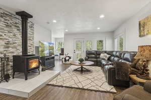 Living room with a wood stove, wood finished floors, and recessed lighting
