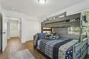 Bedroom with wood finished floors, a textured ceiling, and a closet