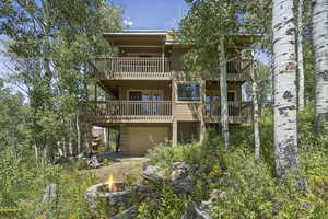 Back of property featuring an outdoor fire pit, a balcony, and a garage