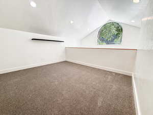 Spare room with vaulted ceiling, a textured ceiling, carpet, and recessed lighting