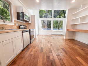 Kitchen with appliances with stainless steel finishes, white cabinetry, light wood-style flooring, decorative backsplash, and recessed lighting