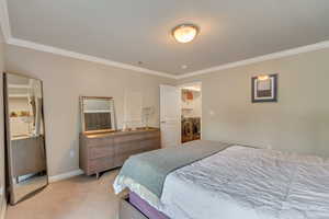 Bedroom with washing machine and clothes dryer, ornamental molding, and light colored carpet
