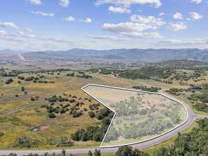 Aerial view of property and surrounding area with property parcel outlined and a mountain backdrop