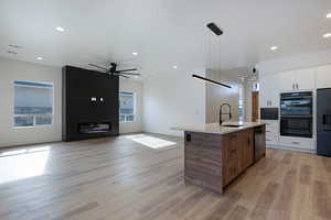 Kitchen featuring open floor plan, modern cabinets, black appliances, light wood-style floors, and recessed lighting