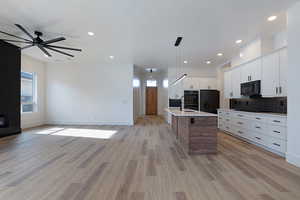 Kitchen featuring a ceiling fan, black appliances, light countertops, open floor plan, and tasteful backsplash