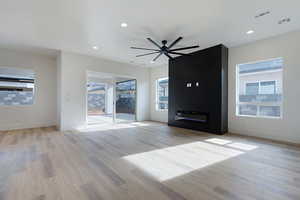 Unfurnished living room with healthy amount of natural light, ceiling fan, light wood-style floors, and recessed lighting
