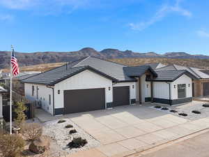 Modern inspired farmhouse with board and batten siding, an attached garage, a mountain view, concrete driveway, and a tiled roof