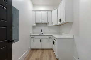 Kitchen featuring light wood-style flooring, light countertops, white cabinetry, and electric panel