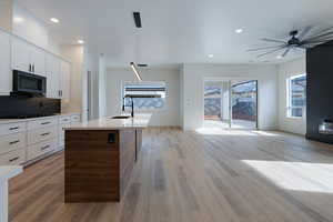 Kitchen with open floor plan, light wood finished floors, decorative backsplash, a ceiling fan, and recessed lighting