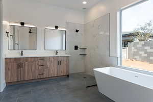 Bathroom with double vanity, a freestanding bath, walk in shower, and recessed lighting