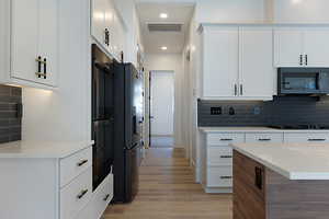 Kitchen featuring decorative backsplash, light wood-style flooring, black appliances, light countertops, and recessed lighting