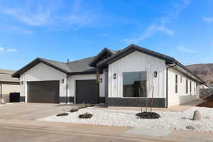 Modern farmhouse with an attached garage, stone siding, driveway, board and batten siding, and a tile roof