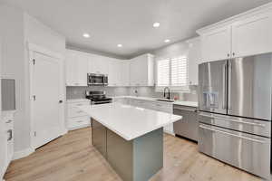 Kitchen with stainless steel appliances, light countertops, and beautiful white cabinetry