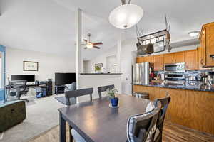 Dining area featuring light wood-style flooring, vaulted ceiling, a desk, and ceiling fan