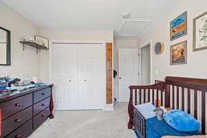 Bedroom featuring light carpet, a closet, and attic access