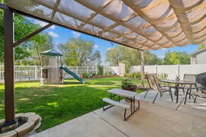 Fenced backyard featuring outdoor dining area, a pergola, a playground, a patio, and grilling area