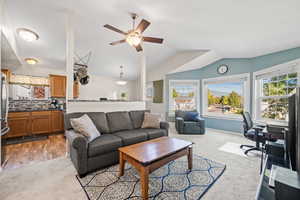 Living area with a ceiling fan, light carpet, plenty of natural light, and vaulted ceiling