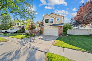 View of front of property featuring driveway, a garage, brick siding, stairway, and stucco siding