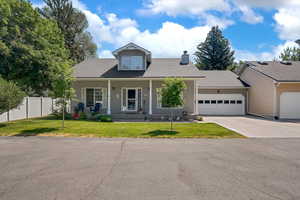 View of front of house with a garage, a chimney, concrete driveway, a shingled roof, and covered porch