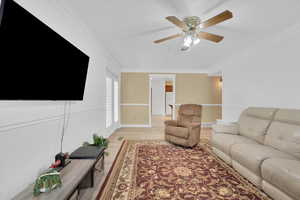 Living room featuring crown molding, ceiling fan, and light wood-style floors