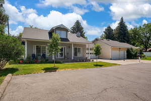 View of front of house with a front lawn, concrete driveway, a chimney, an attached garage, and roof with shingles