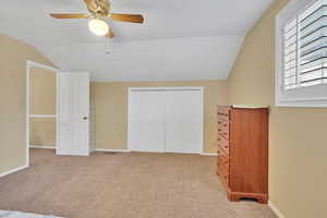 Unfurnished bedroom with lofted ceiling, carpet flooring, a closet, and ceiling fan