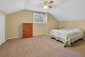 Carpeted bedroom with vaulted ceiling and a ceiling fan