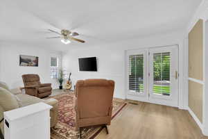 Living room featuring light wood-style floors, crown molding, and a ceiling fan