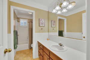 Full bath featuring vanity, a chandelier, ornamental molding, and shower / tub combo with curtain