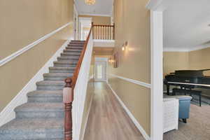 Staircase with wood finished floors and crown molding