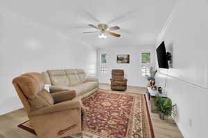 Living room with crown molding, a ceiling fan, and light wood-style floors
