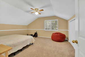 Carpeted bedroom with lofted ceiling and a ceiling fan