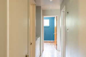 Hallway with separate washer and dryer and light tile patterned floors
