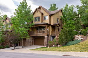 Craftsman inspired home featuring stairs, concrete driveway, a garage, and stone siding