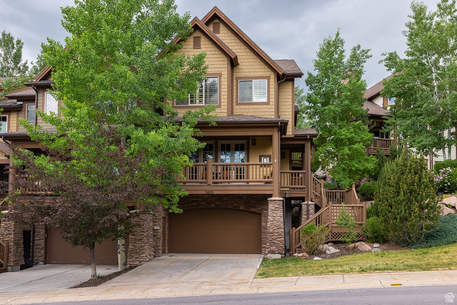 Craftsman-style home with a garage, driveway, stone siding, stairway, and a porch