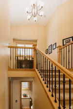 Stairway featuring a chandelier and high vaulted ceiling