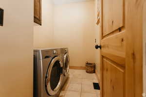 Washroom with washer and clothes dryer, cabinet space, and light tile patterned floors