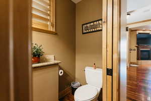 Half bath featuring wood finished floors and a glass covered fireplace