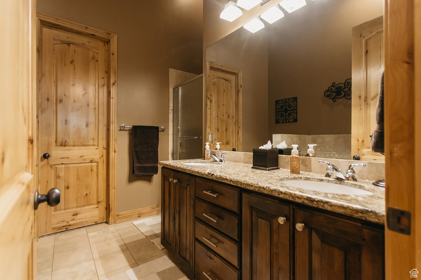 Bathroom featuring tile patterned floors, double vanity, and a shower with shower door