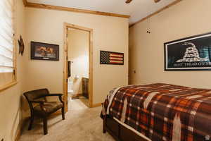 Bedroom with ornamental molding, light colored carpet, connected bathroom, and a ceiling fan