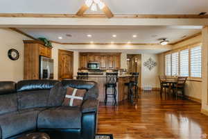 Living room featuring crown molding, dark wood-type flooring, a ceiling fan, and recessed lighting
