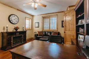 Living area featuring wood finished floors, a ceiling fan, and ornamental molding