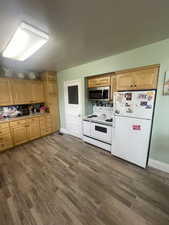 Kitchen featuring white appliances and dark wood finished floors