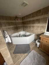 Full bathroom featuring a tub to relax in, tile walls, a shower, and vanity