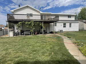 Rear view of property with a deck, a lawn, and a patio