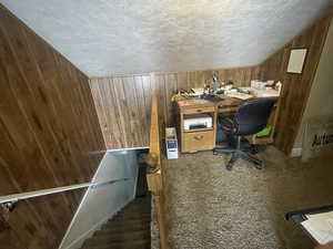 Office space featuring wood walls and a textured ceiling