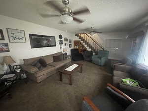 Living room featuring a ceiling fan, carpet, stairs, and a textured ceiling