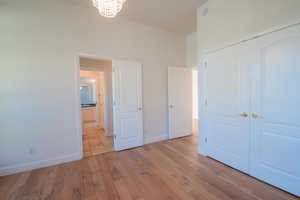 Unfurnished bedroom with a chandelier, light wood-style flooring, and a closet