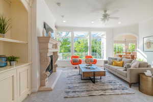 Living area with ornamental molding, light carpet, ceiling fan, a high end fireplace, and recessed lighting